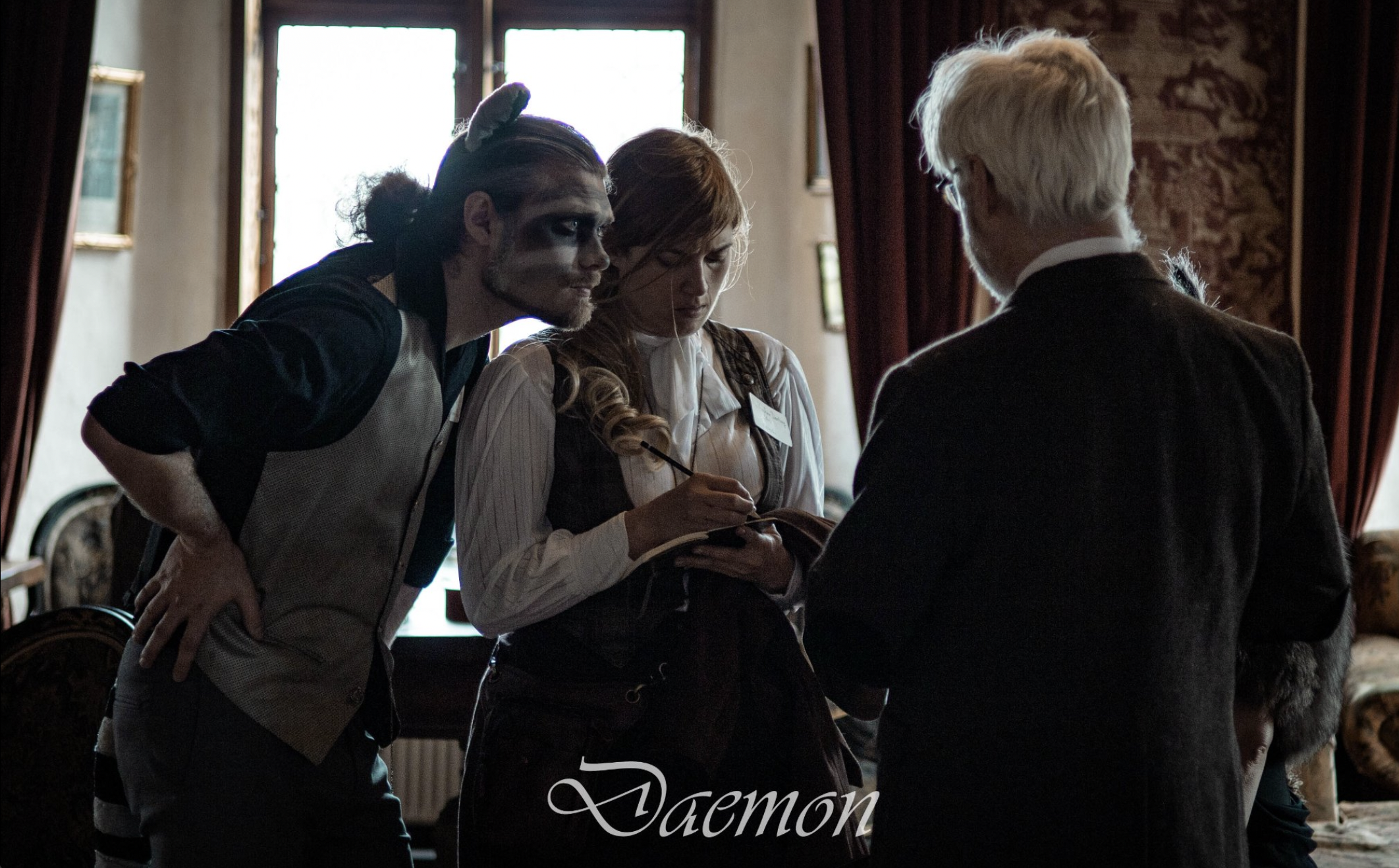 Daemon staring intensivly someone who talks and daemon's human making notes.